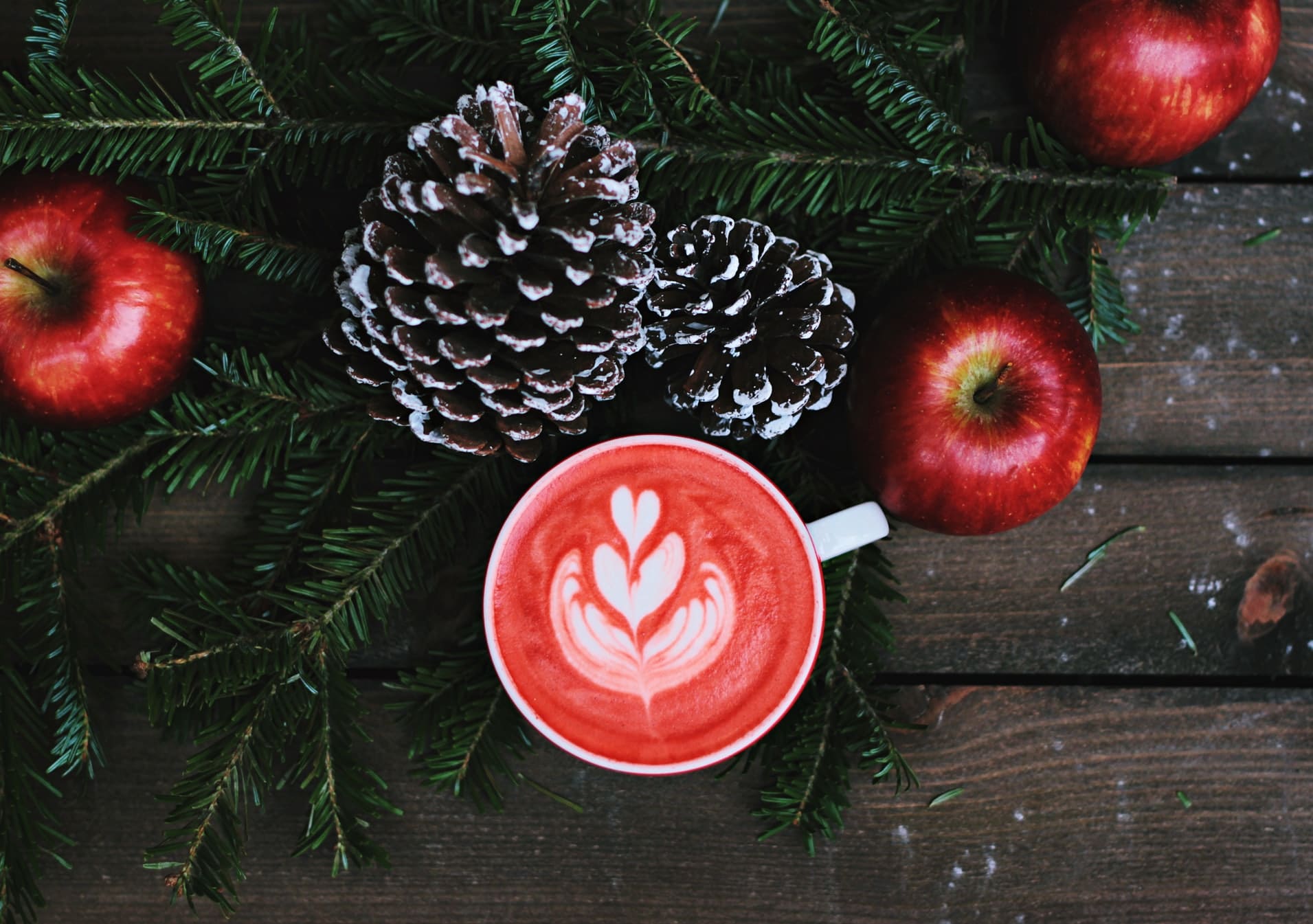 елочная ветка, яблоки и напиток на деревянной поверхности создают рождественскую атмосферу