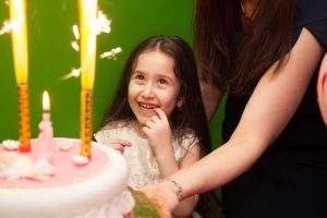 девочка загадывает жеоание перед тем как задуть свечи на торте