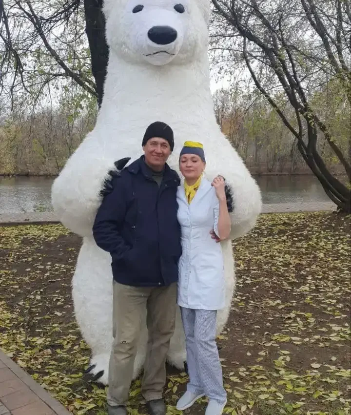 пара в парке позирует н фоне белого медведя